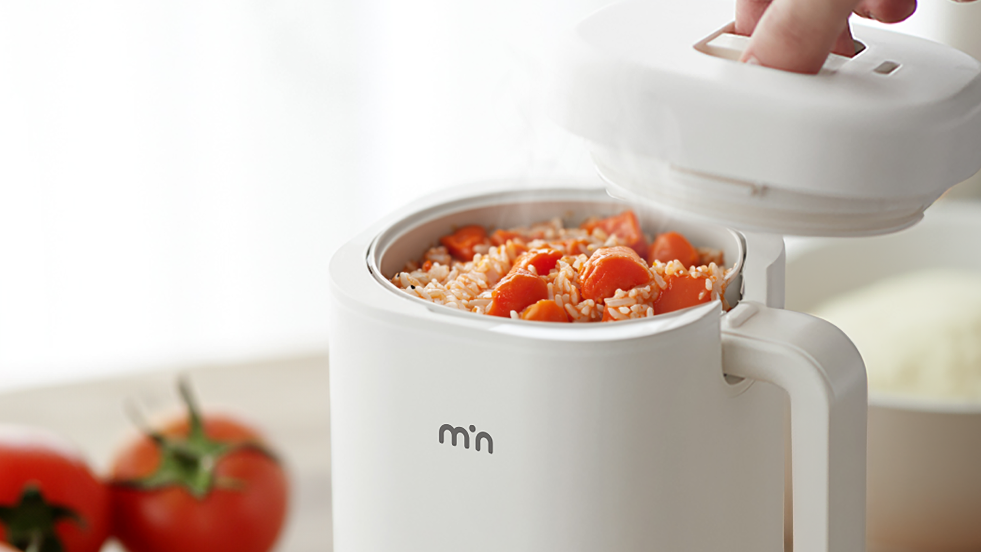 tomato rice crushed and stirred inside min mini rice cooker with a bowl of rice and 2 tomatoes on the side